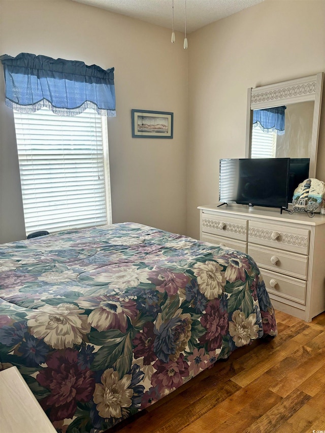 bedroom with a textured ceiling, hardwood / wood-style floors, and multiple windows