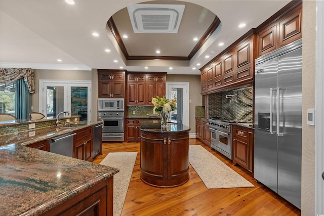 9400 Lake Dr, Myrtle Beach, SC 29572 - kitchen featuring ornamental molding, a raised ceiling, light wood-style floors, a large island with sink, and built in appliances