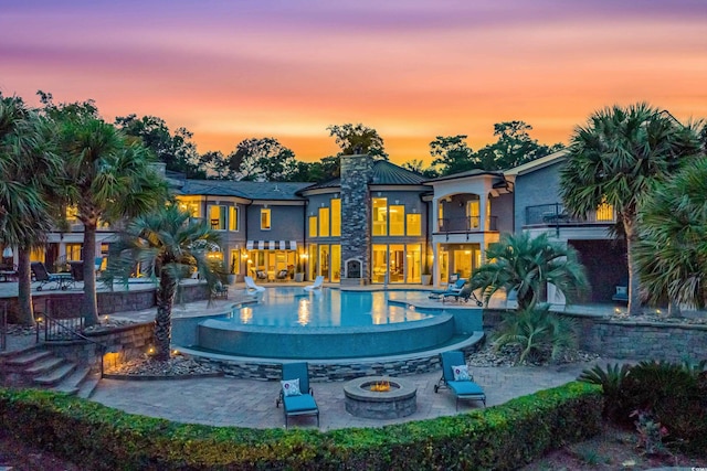9400 Lake Dr, Myrtle Beach, SC 29572 - rear view of property featuring a patio area, an outdoor fire pit, a chimney, a balcony, and an infinity pool