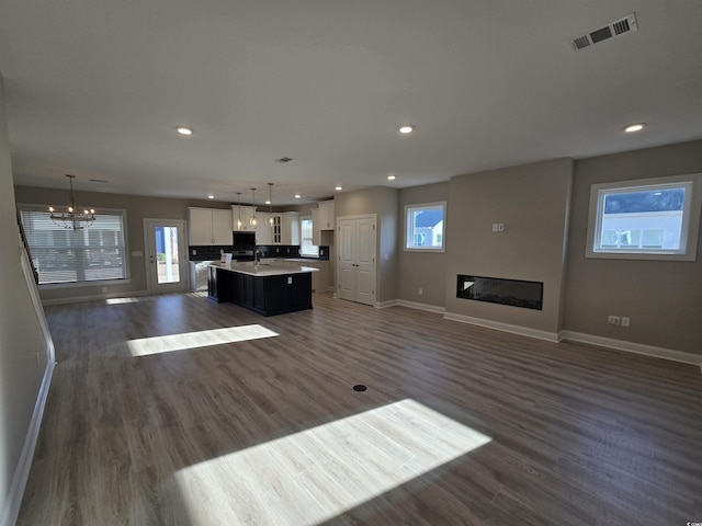 unfurnished living room featuring sink, a chandelier, and dark hardwood / wood-style floors