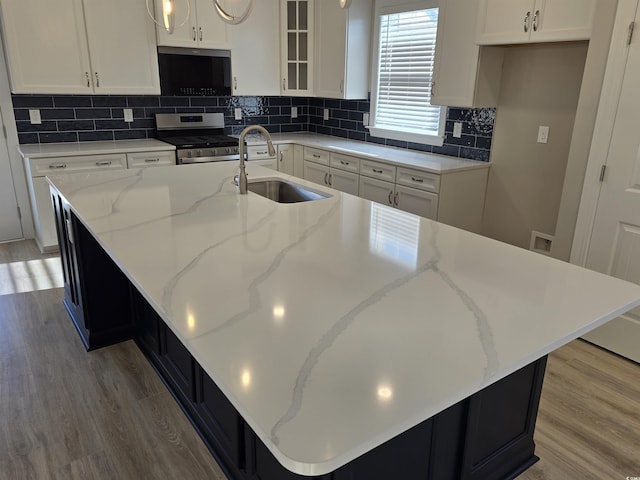 kitchen with stainless steel gas range oven, a kitchen island with sink, and sink