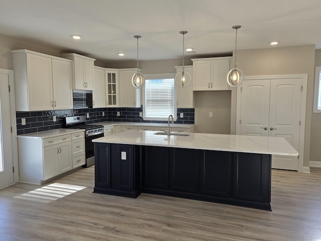 kitchen featuring white cabinetry, stainless steel gas range, and a kitchen island with sink