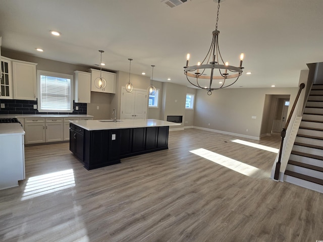 kitchen with a center island, pendant lighting, hardwood / wood-style flooring, white cabinets, and tasteful backsplash