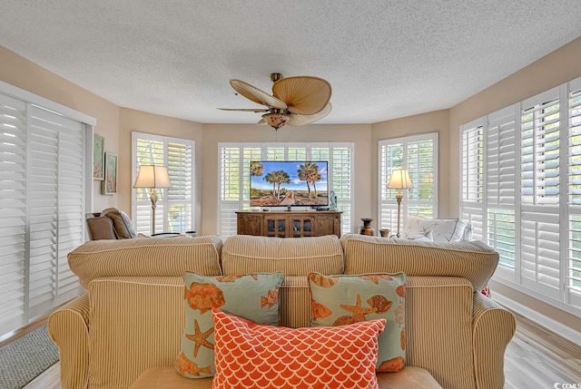 living room with wood-type flooring, ceiling fan, and a textured ceiling