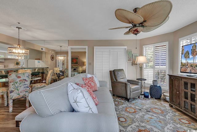 living room featuring wood-type flooring and ceiling fan with notable chandelier