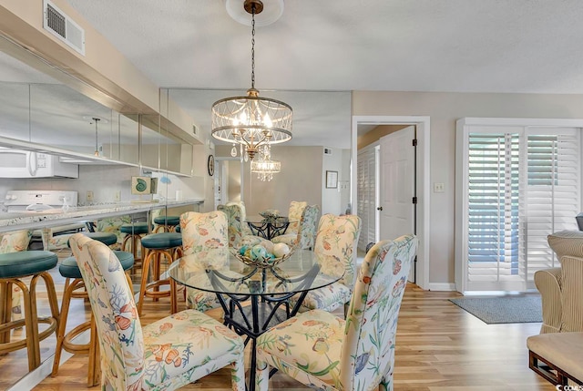 dining area with light hardwood / wood-style floors and a chandelier