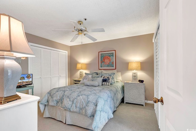 carpeted bedroom with a closet, ceiling fan, and a textured ceiling