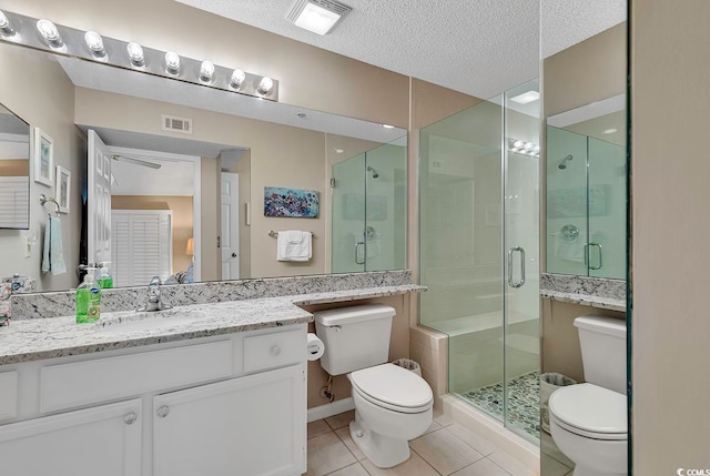 bathroom with tile flooring, large vanity, a textured ceiling, toilet, and a shower with shower door