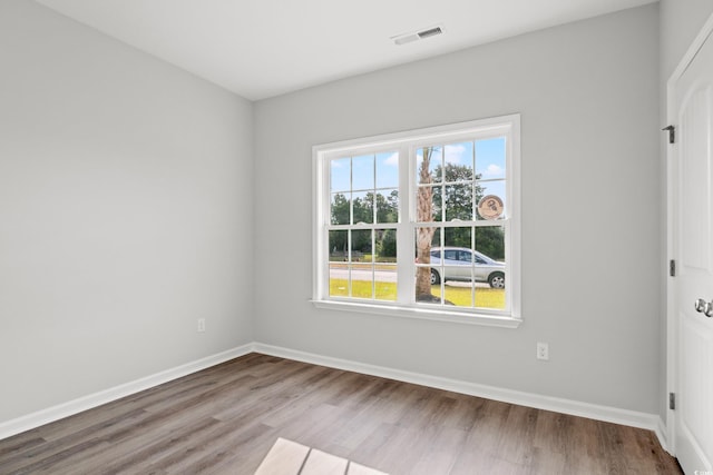 empty room with baseboards, wood finished floors, and visible vents
