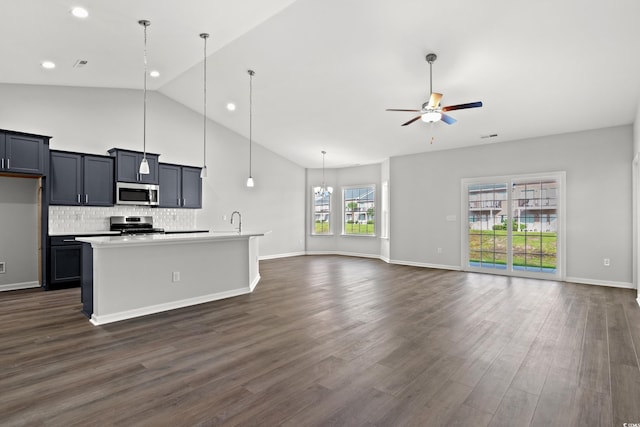 kitchen with a kitchen island with sink, backsplash, appliances with stainless steel finishes, ceiling fan with notable chandelier, and open floor plan
