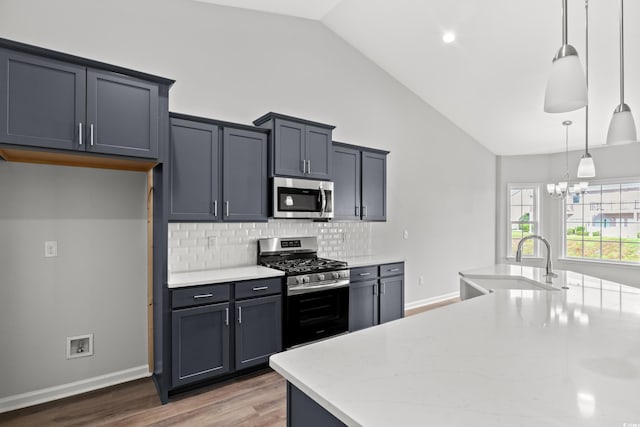 kitchen with decorative backsplash, appliances with stainless steel finishes, wood finished floors, a sink, and a chandelier