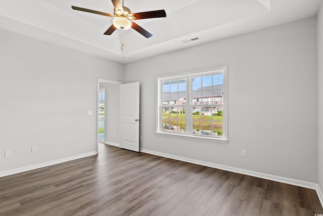 unfurnished room featuring visible vents, a raised ceiling, dark wood-style flooring, and ceiling fan
