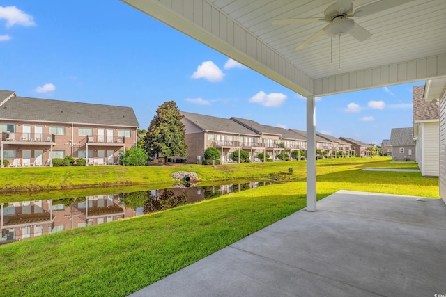 view of yard with a residential view, ceiling fan, a water view, and a patio area