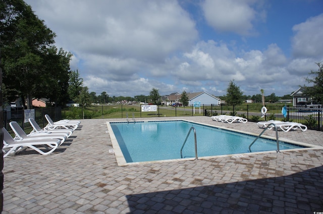 community pool with a patio and fence