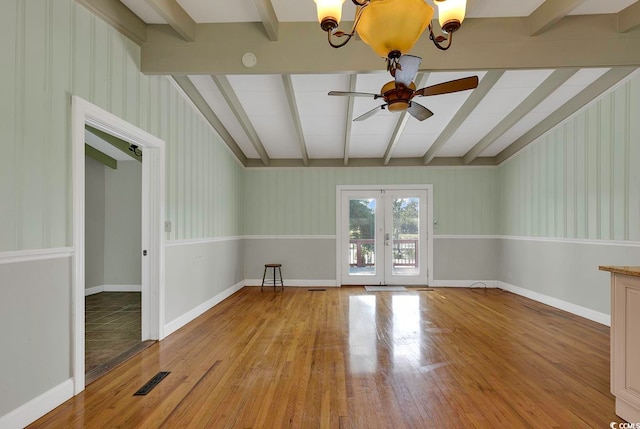 unfurnished room featuring beamed ceiling, hardwood / wood-style floors, ceiling fan with notable chandelier, and french doors