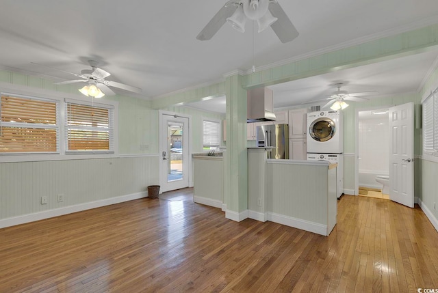 kitchen featuring ceiling fan, light hardwood / wood-style floors, stacked washing maching and dryer, and stainless steel fridge