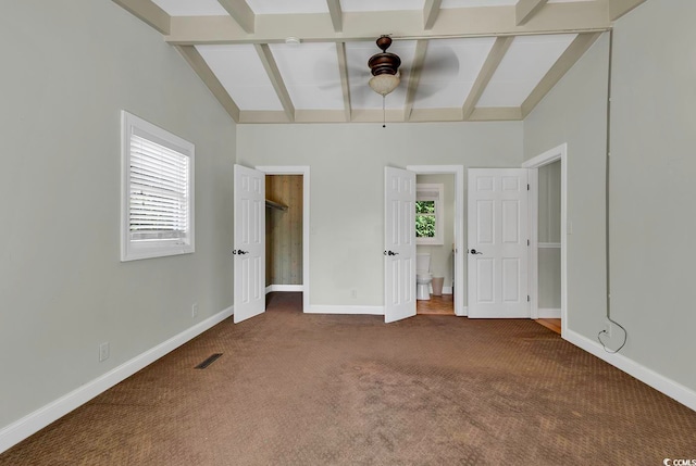 unfurnished bedroom with dark colored carpet, lofted ceiling with beams, and ceiling fan