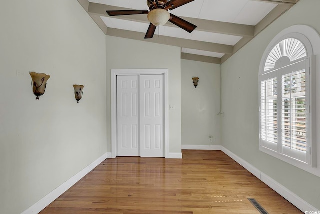 unfurnished bedroom with lofted ceiling with beams, light hardwood / wood-style flooring, and ceiling fan