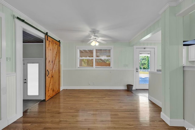 spare room with hardwood / wood-style floors, ceiling fan, crown molding, and a barn door