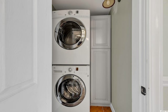 washroom featuring cabinets, stacked washer / dryer, and tile floors