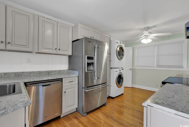 kitchen featuring light wood-type flooring, white cabinetry, stacked washer and clothes dryer, stainless steel appliances, and ceiling fan