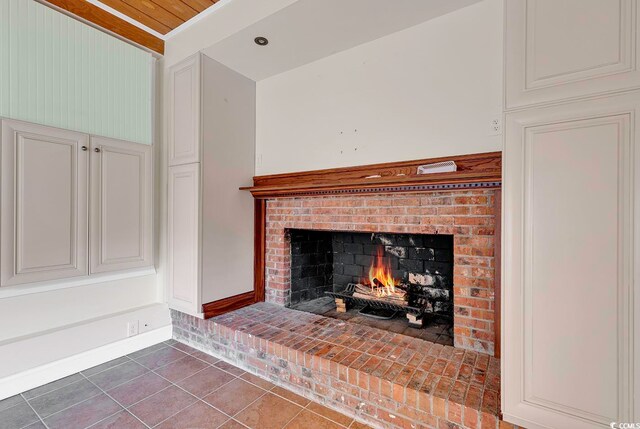 details with wooden ceiling, dark tile flooring, and a brick fireplace