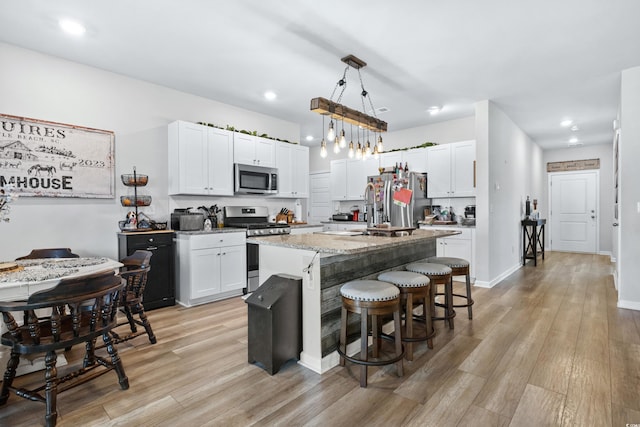 kitchen featuring pendant lighting, light hardwood / wood-style floors, a kitchen island, white cabinetry, and stainless steel appliances