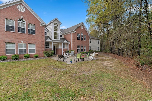 rear view of house featuring brick siding, a lawn, and a patio area