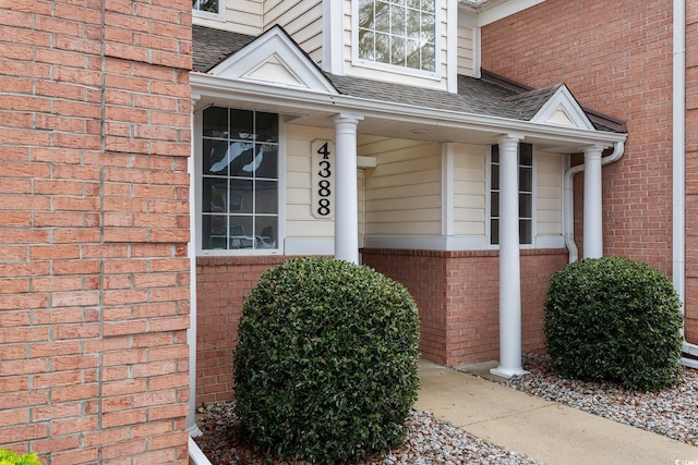 property entrance with a shingled roof and brick siding