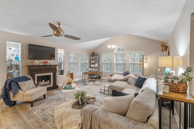 living room with a wealth of natural light, a fireplace with raised hearth, lofted ceiling, and light wood finished floors