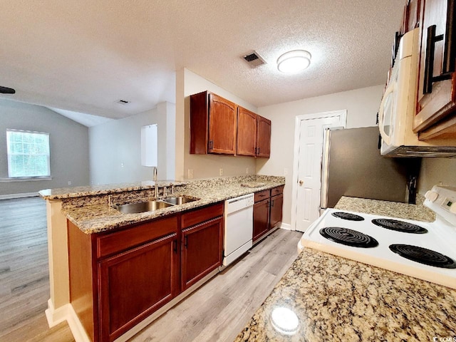 kitchen with white appliances, visible vents, a peninsula, light wood-style floors, and a sink