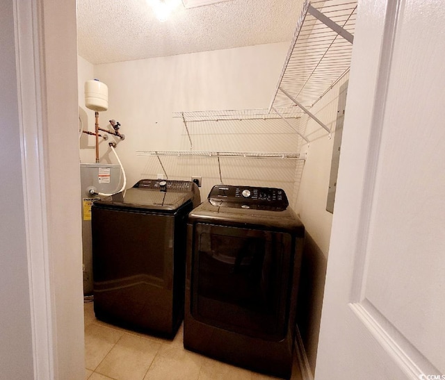 laundry room with light tile patterned floors, water heater, washing machine and dryer, a textured ceiling, and laundry area