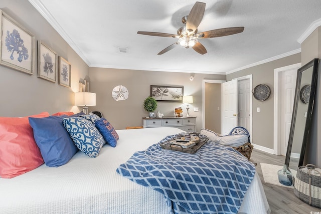 bedroom with baseboards, visible vents, wood finished floors, a textured ceiling, and crown molding