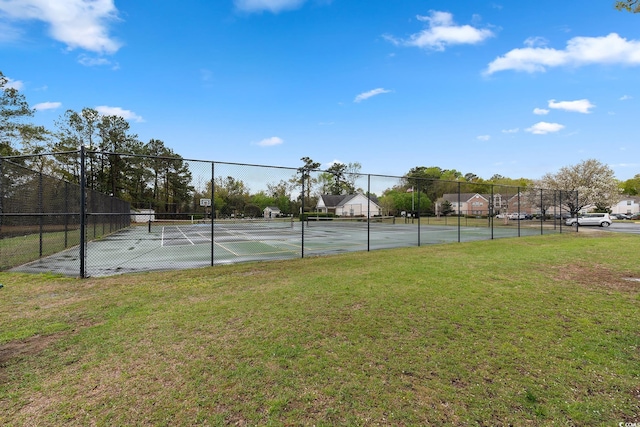 view of tennis court featuring a yard and fence