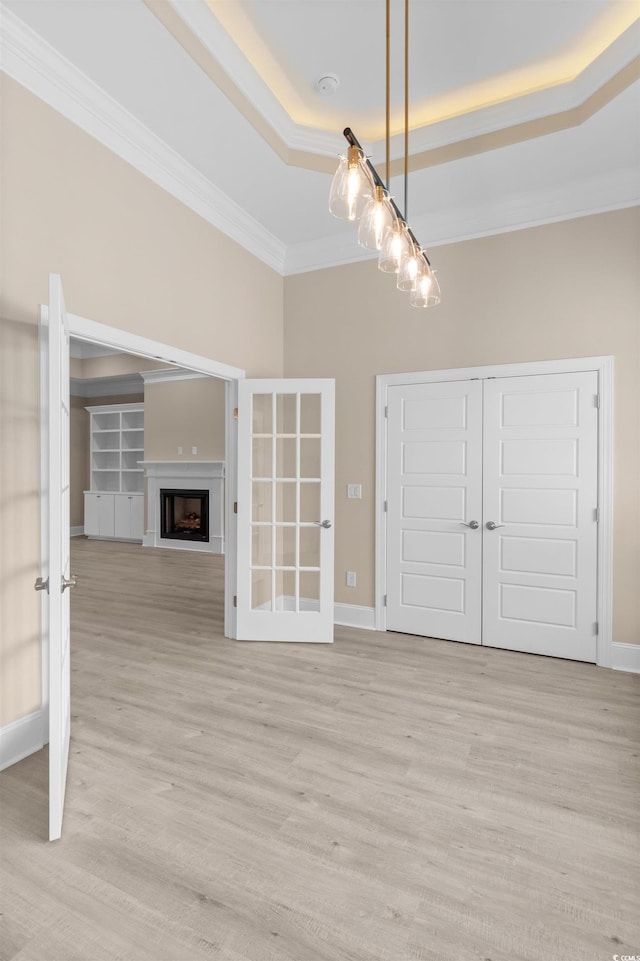 interior space featuring a raised ceiling, crown molding, and light wood-type flooring