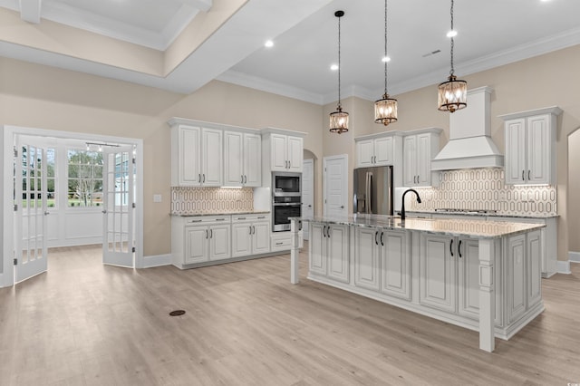 kitchen with custom exhaust hood, white cabinets, hanging light fixtures, and appliances with stainless steel finishes