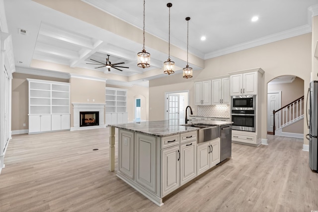 kitchen featuring tasteful backsplash, coffered ceiling, an island with sink, stainless steel appliances, and light stone counters