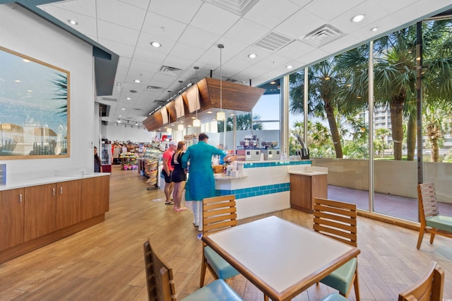 interior space featuring floor to ceiling windows, a drop ceiling, and light wood-type flooring