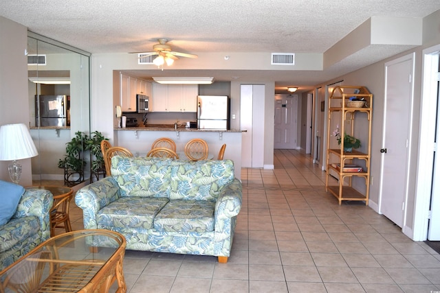 tiled living room with ceiling fan and a textured ceiling