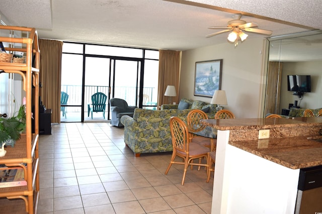 living room featuring floor to ceiling windows, ceiling fan, light tile patterned floors, and a textured ceiling