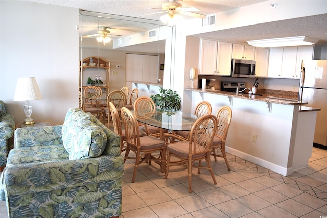 tiled dining area with ceiling fan, sink, and a textured ceiling