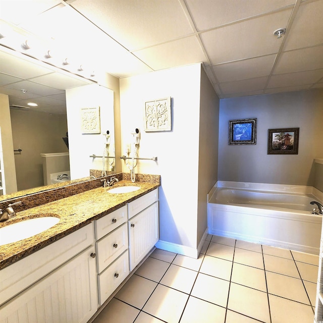 bathroom with tile patterned floors, a tub to relax in, vanity, and a drop ceiling