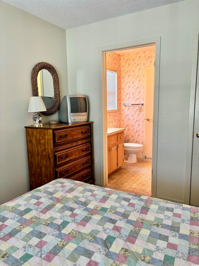 bedroom with a textured ceiling, light tile floors, and ensuite bathroom