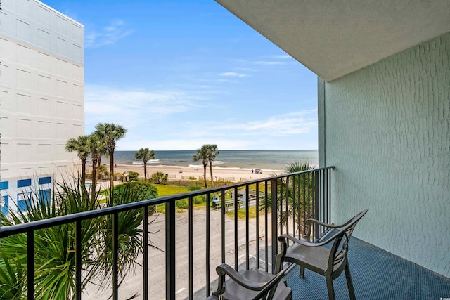 balcony with a water view and a view of the beach