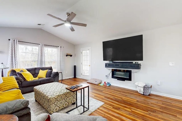 living room with ceiling fan, light hardwood / wood-style floors, and vaulted ceiling