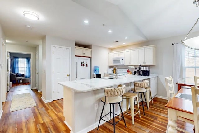 kitchen featuring white cabinetry, kitchen peninsula, light wood-type flooring, and white appliances