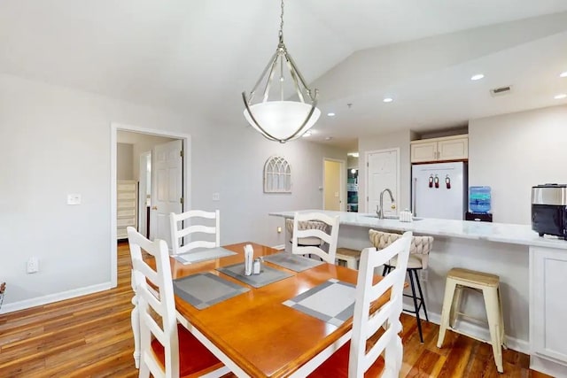 dining room featuring sink, lofted ceiling, and wood-type flooring