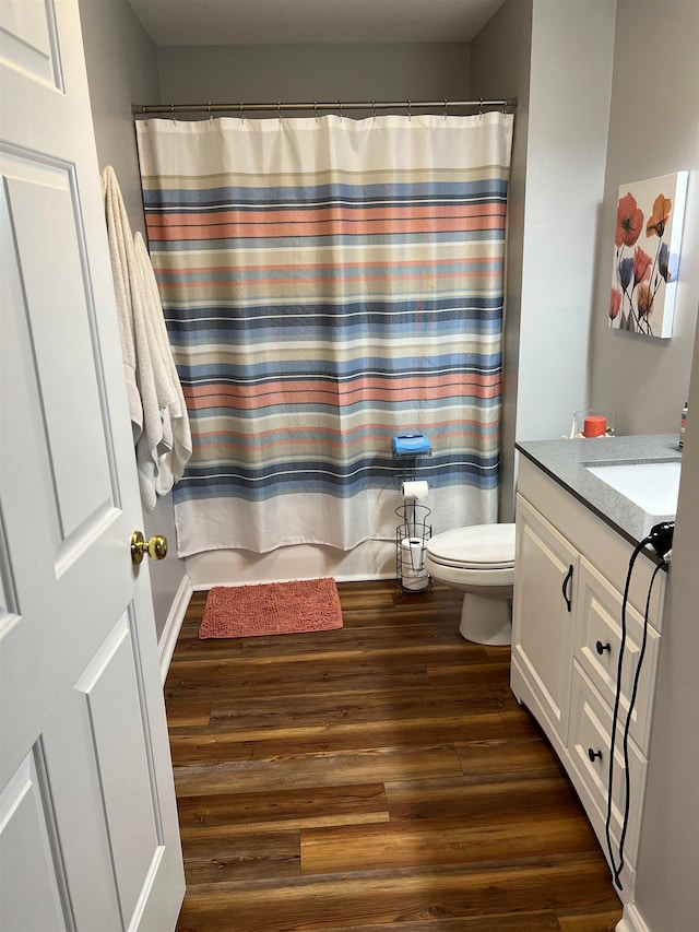 bathroom featuring hardwood / wood-style flooring, vanity, walk in shower, and toilet