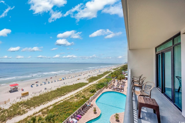 balcony with a community pool, a patio, a view of the beach, and a water view