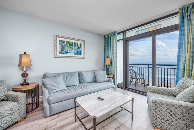 living room featuring floor to ceiling windows, wood-type flooring, and a water view